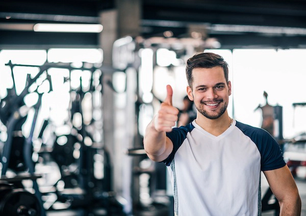 smiling sportsman showing thumbs up at the gym.